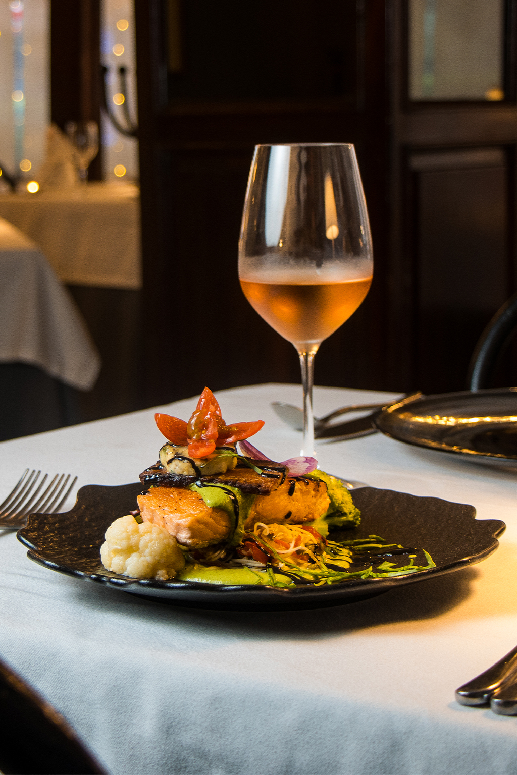 Salmón con vegetales y copa de vino en Kaiser Maximilian Puerto Vallarta